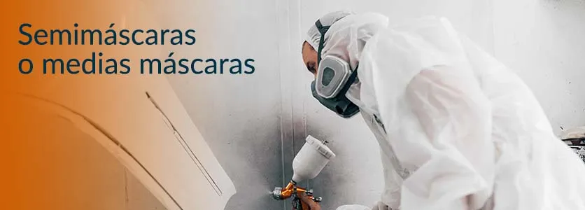 Pintor industrial aplicando pintura con semimáscara respiratoria de protección